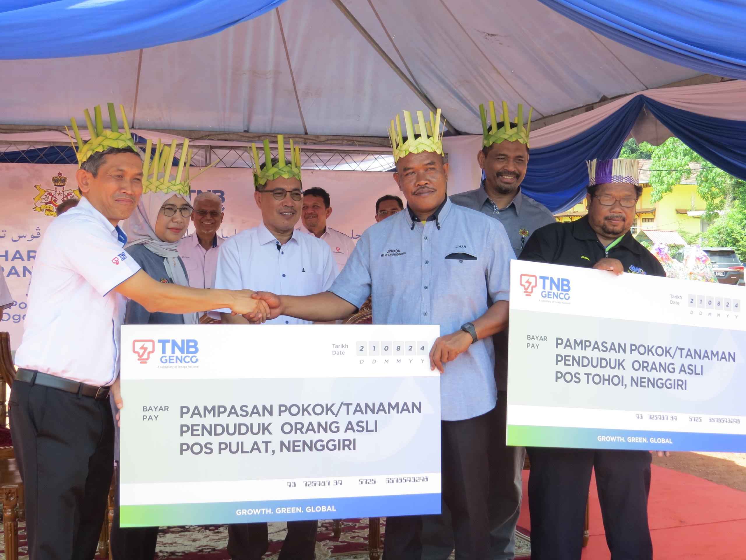 Muhamad Nazri kiri menyampaikan replika cek pampasan penduduk kepada Liman di Pos Tohoi Gua Musang hari ini. Foto oleh AIMUNI TUAN LAH