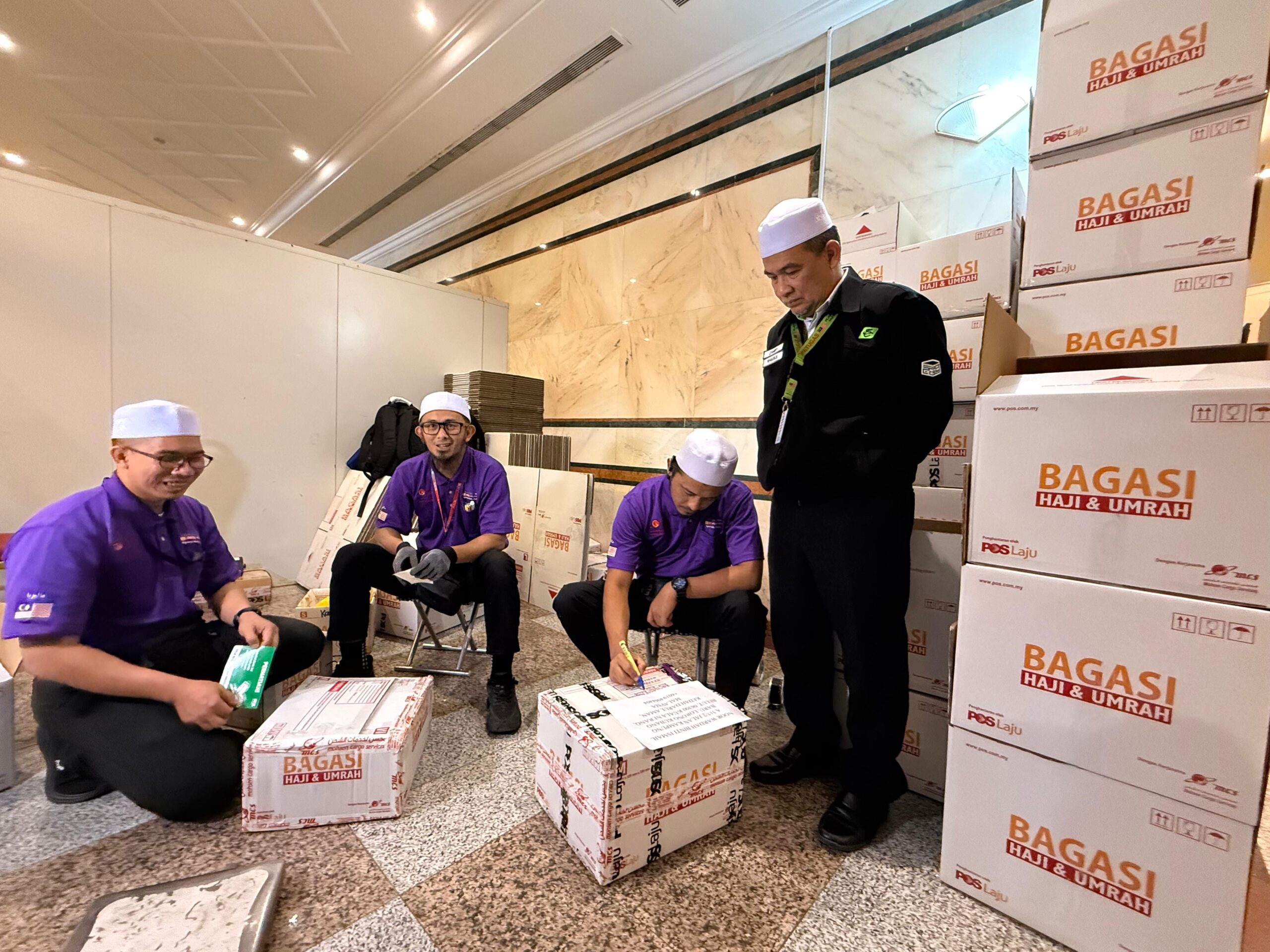 MOHAMAD ZAMRY (kanan) ketika memantau petugas Pos Malaysia membungkus barangan para jemaah di Abraj Al Janadriyah, Mekah baru-baru ini.