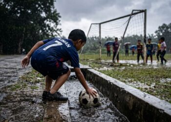 Ibu bapa di tempat kerja, anak main bola dalam hujan