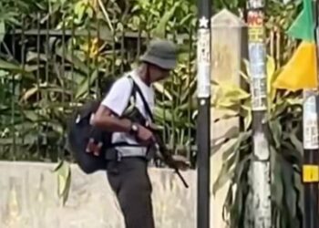 Lelaki santai berjalan sambil bawa senapang