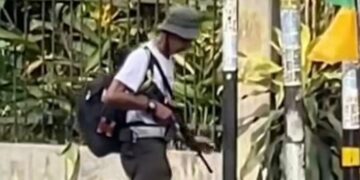 Lelaki santai berjalan sambil bawa senapang